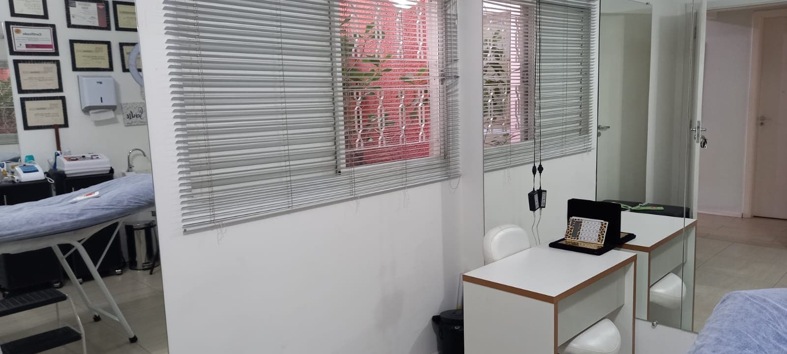 Sala com certificados na parede, maca e bancada branca