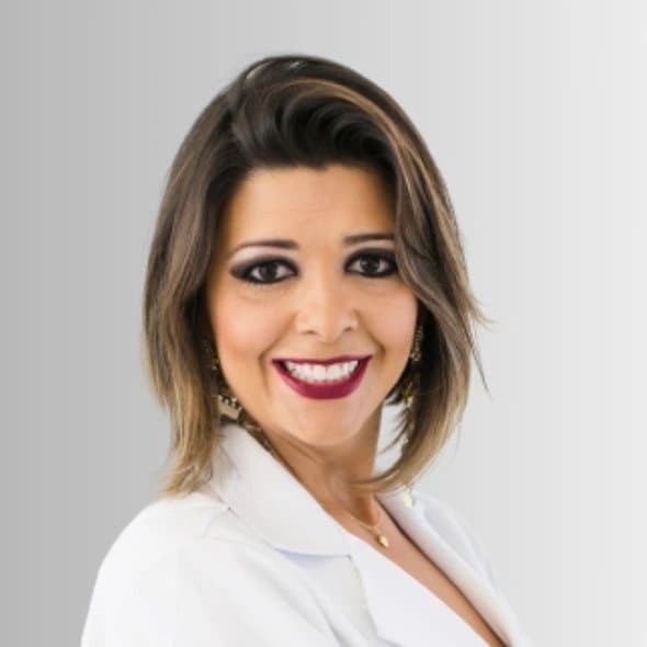 Alessandra Hengler sorrindo, de jaleco branco, em retrato de estúdio